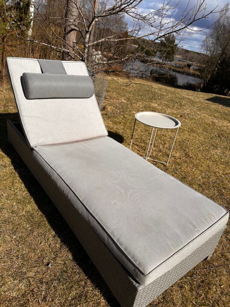 Aurinkopeti ja kirpputorilta löytynyt painotyyny keväisellä pihalla merimaisemassa.